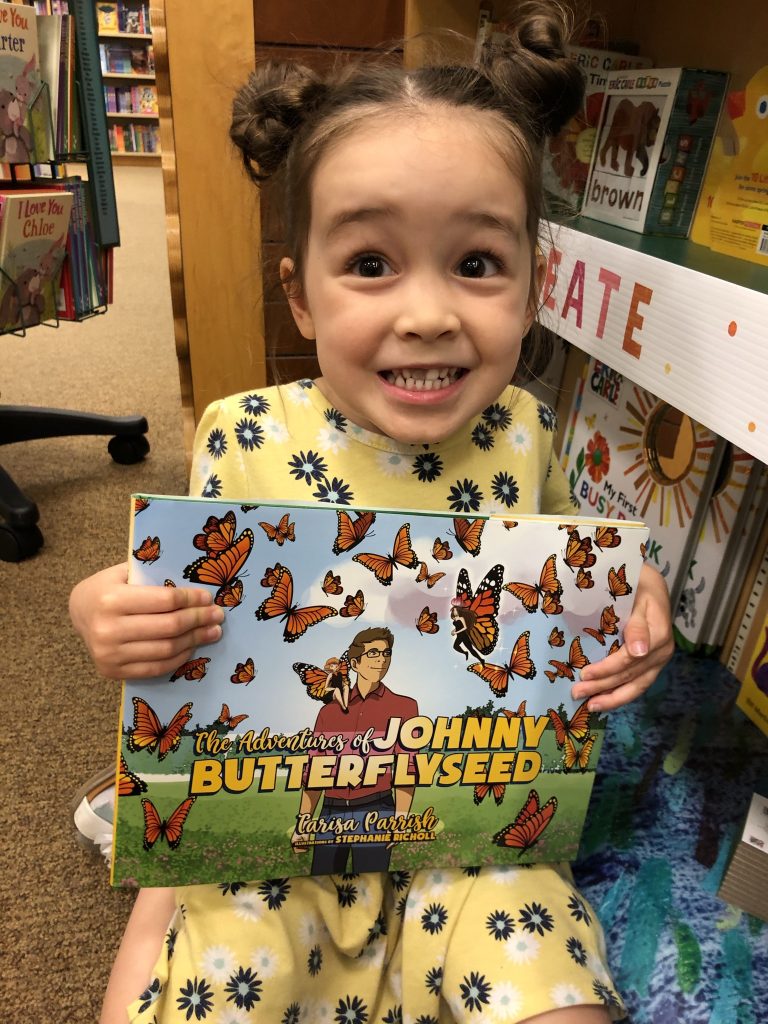 Cute Girl holding 'The Adventures of Johnny Butterflyseed' book.